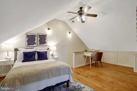 a bedroom with a bed a desk and chair with wooden floor