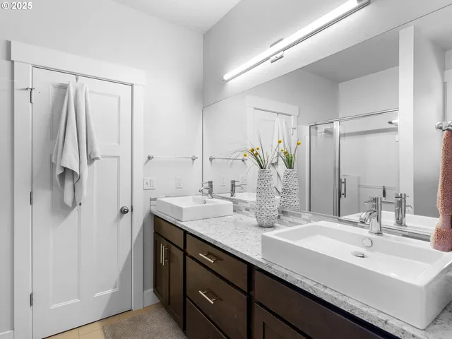 a bathroom with a double vanity sink mirror and shower