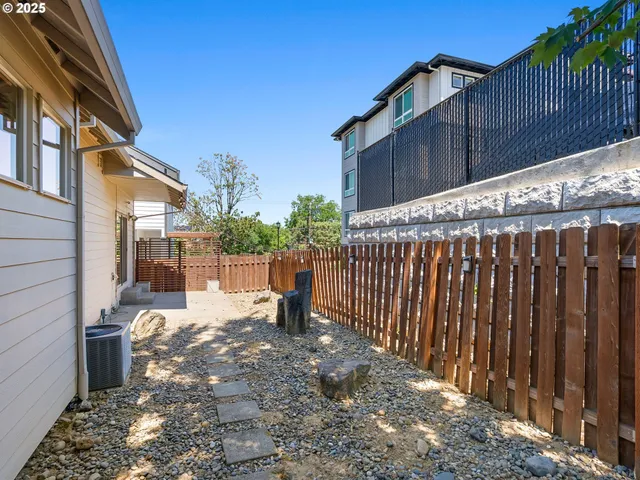 a view of a backyard with a tree and wooden fence
