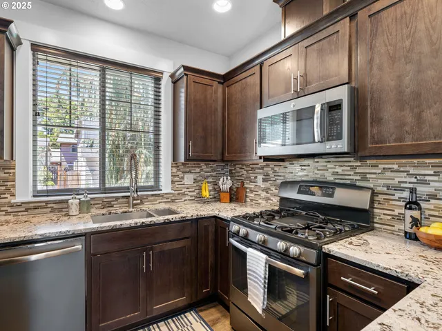 a kitchen with stainless steel appliances granite countertop a stove sink microwave and cabinets