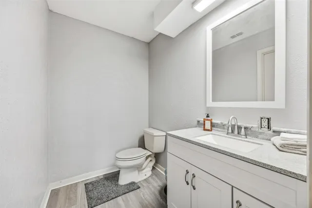 a bathroom with a granite countertop sink a toilet and a mirror