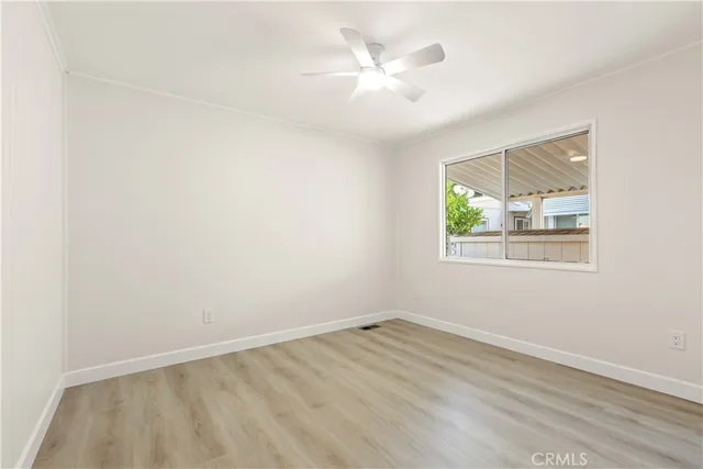 an empty room with wooden floor chandelier fan and windows