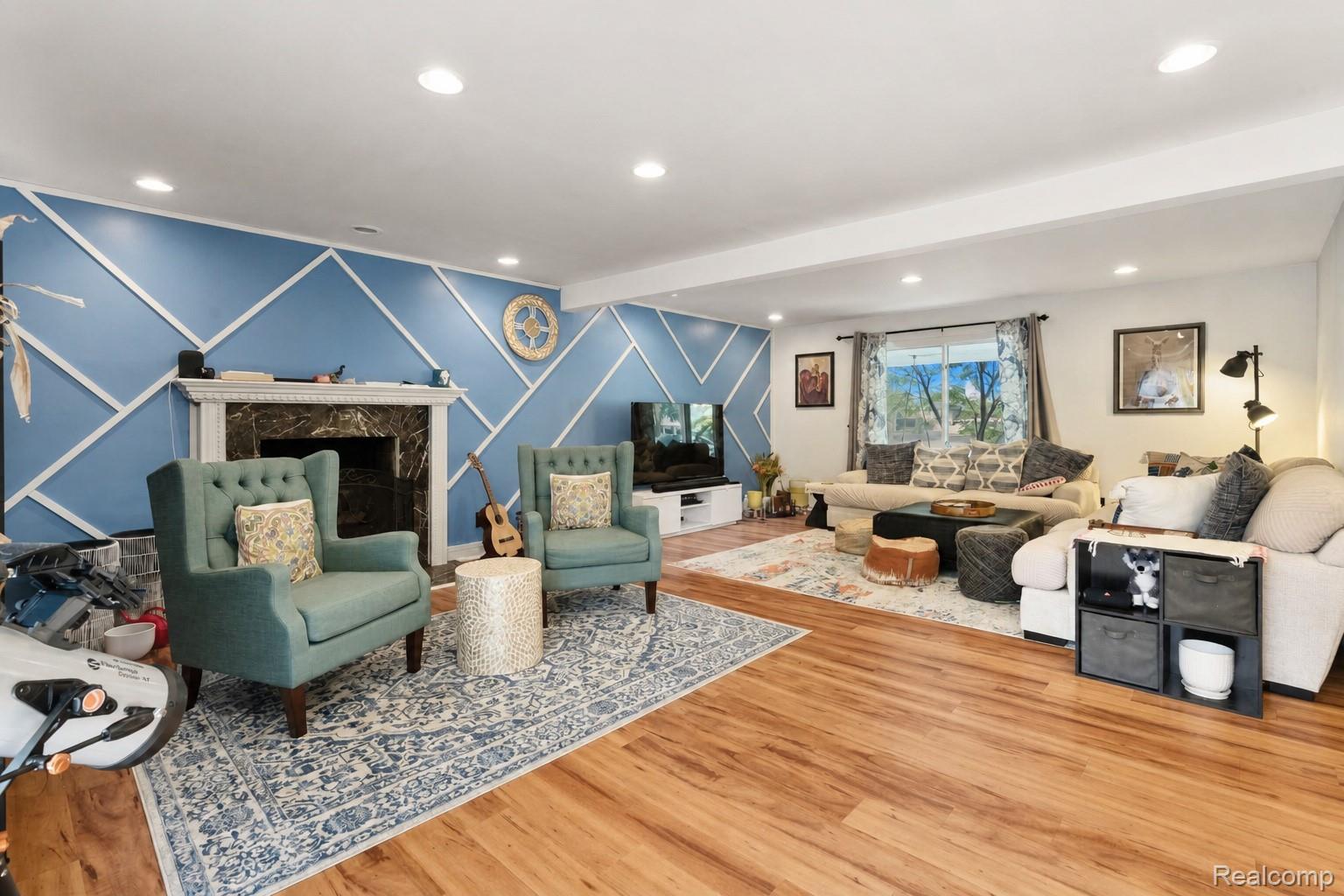 2247 West Maple Road Birmingham, MI 48009 - Photo 10 of 46 Spacious interior featuring wood-finish flooring, recessed lighting, a decorative fireplace with a stone surround, and a wall with geometric trim