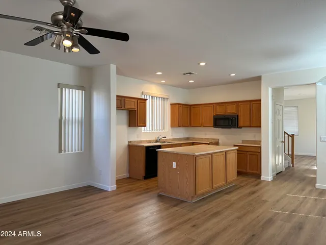 a kitchen with stainless steel appliances a stove top oven a sink dishwasher and a refrigerator with wooden floor