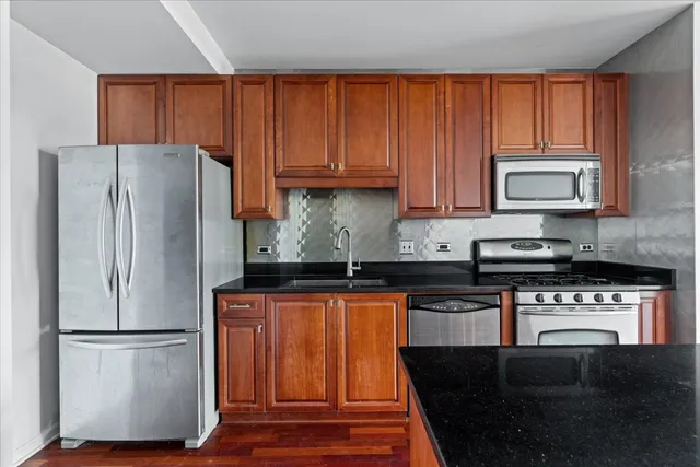 a kitchen with granite countertop wooden cabinets and a refrigerator