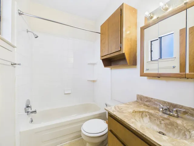 a bathroom with a granite countertop sink toilet and shower