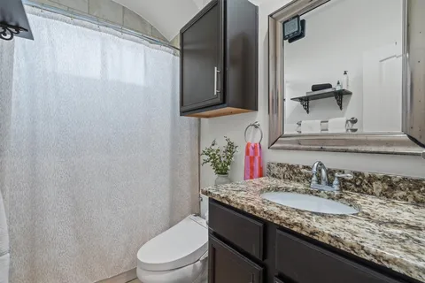 a bathroom with a granite countertop sink toilet and mirror