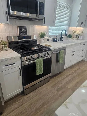 a kitchen with stainless steel appliances a stove a sink and wooden cabinets