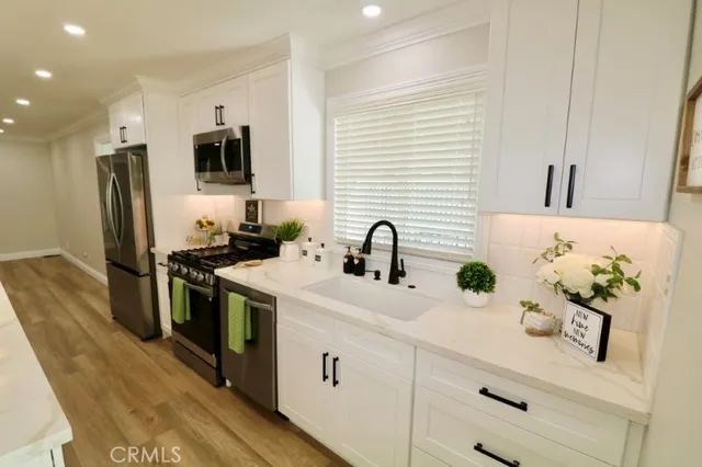 a kitchen with stainless steel appliances kitchen island granite countertop a sink a stove and a refrigerator