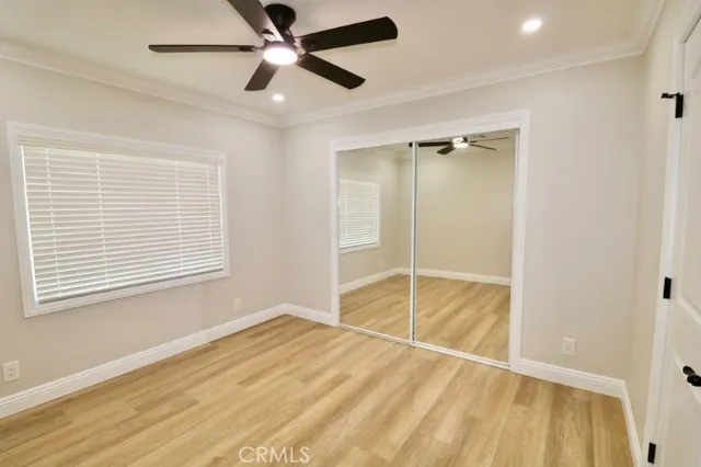 a view of empty room with wooden floor and fan