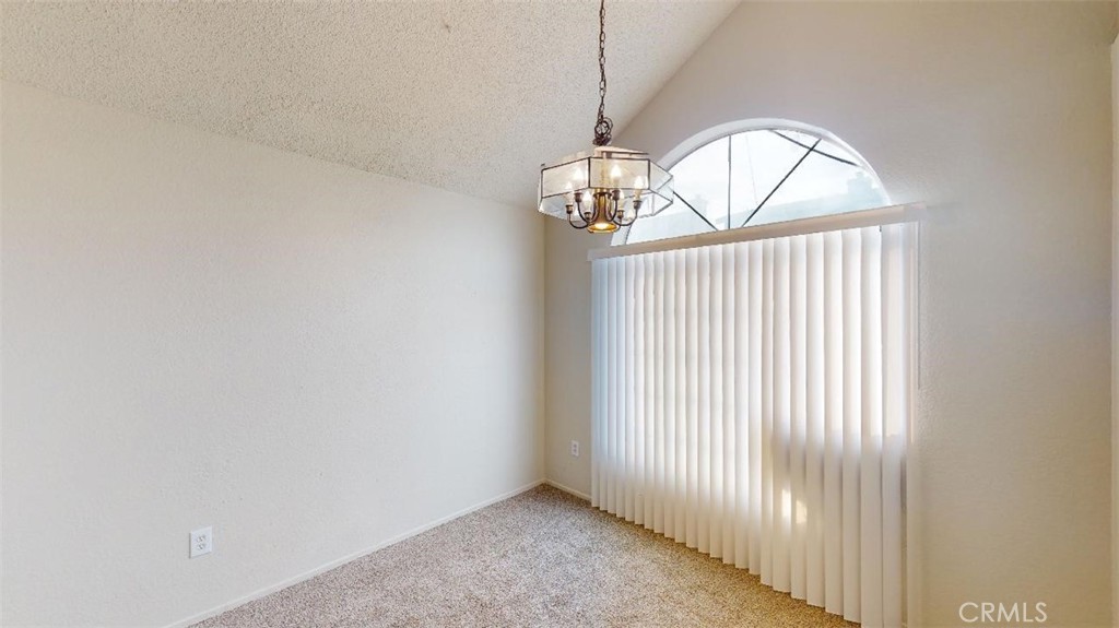 12246 Pluto Drive Victorville, CA 92392 - Photo 2 of 64 an empty room with a chandelier fan and windows