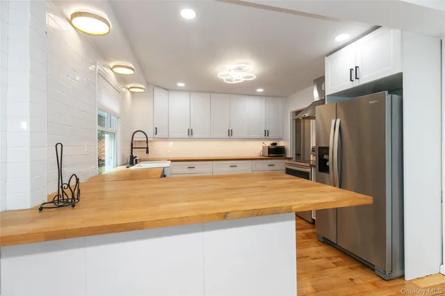 a large kitchen with kitchen island a refrigerator a sink and a stove