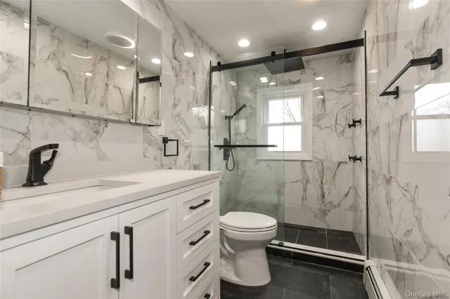 a bathroom with a shower sink vanity and toilet