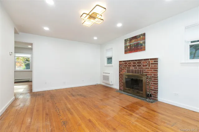 a view of empty room with wooden floor fireplace and window