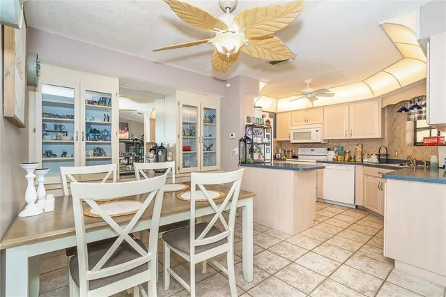 a kitchen with stainless steel appliances granite countertop a dining table chairs and white cabinets
