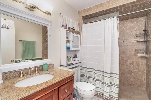 a bathroom with a granite countertop sink toilet a mirror and shower