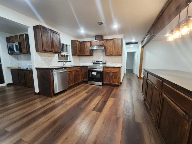 a kitchen with granite countertop a refrigerator and a stove top oven