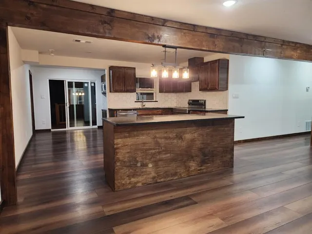 a large white kitchen with kitchen island granite countertop a sink and a stove