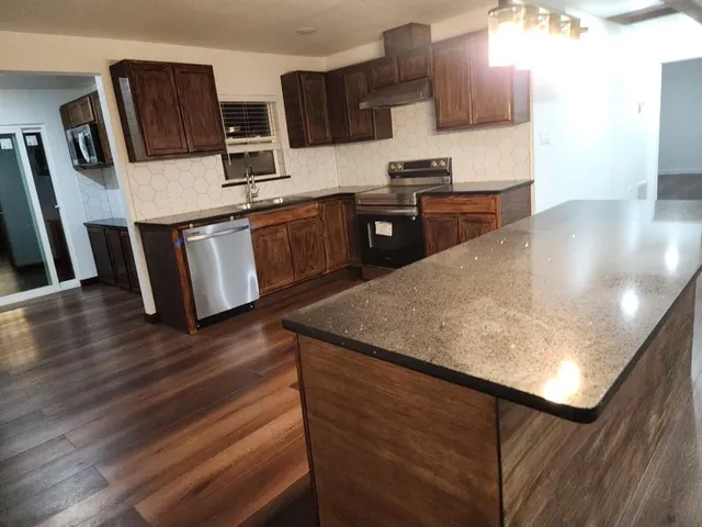 a kitchen with stainless steel appliances granite countertop a stove a sink and a microwave