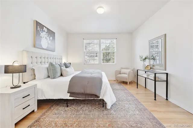 a spacious bedroom with a bed a couch and paintings on the wall