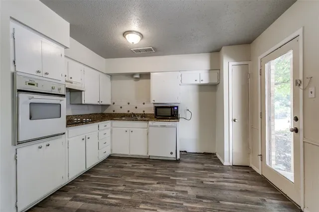 a kitchen with granite countertop white cabinets and white appliances