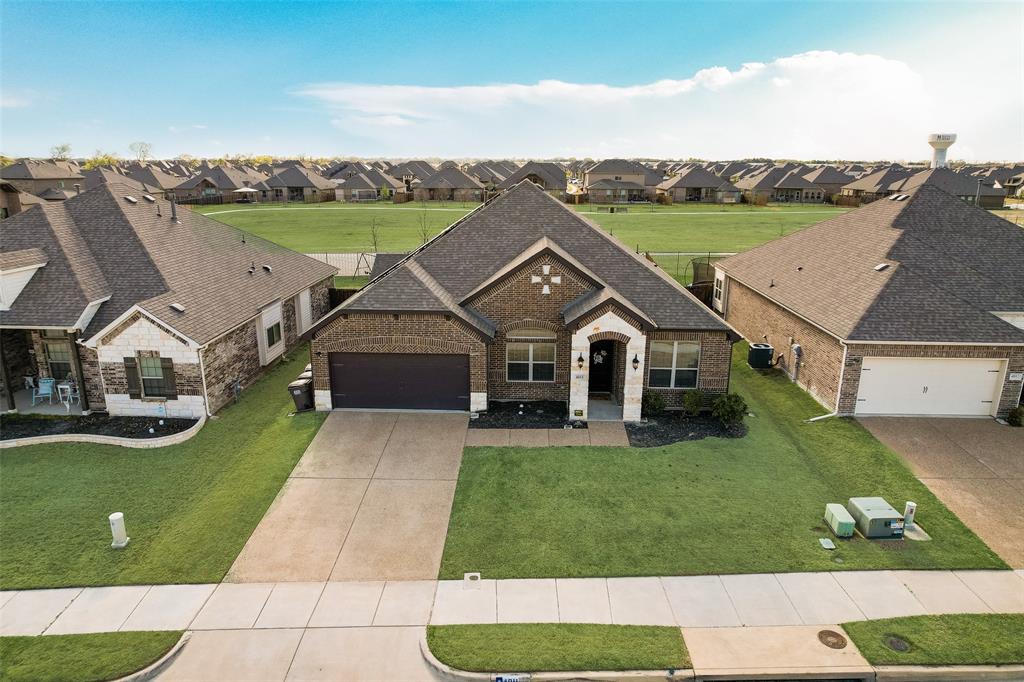 French provincial home with a front yard, roof with shingles, concrete driveway, brick siding, and a residential view
