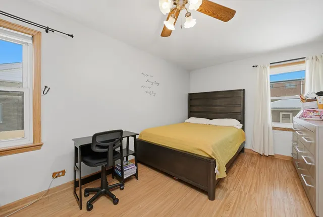 a bedroom with a bed a desk and chair with wooden floor