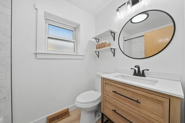 a bathroom with a granite countertop toilet sink mirror and vanity