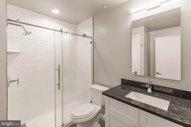a bathroom with a granite countertop sink toilet and shower