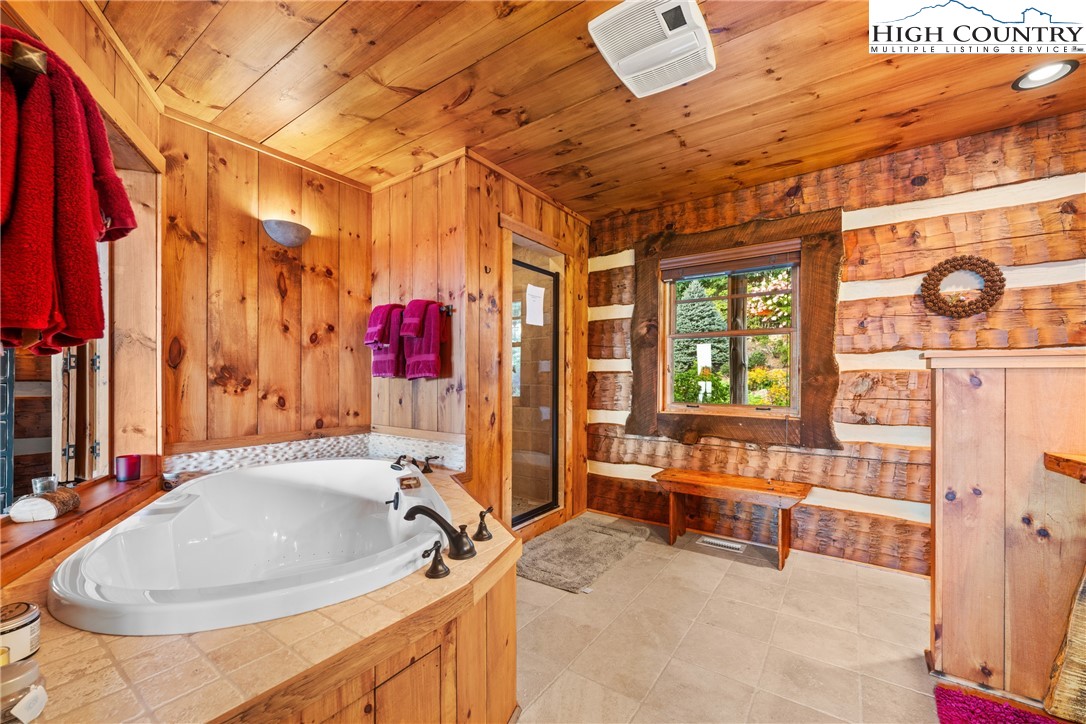333 Windy Ridge Road Vilas, NC 28692 - Photo 26 of 46 a bathroom with a tub a sink and a large mirror next to a window