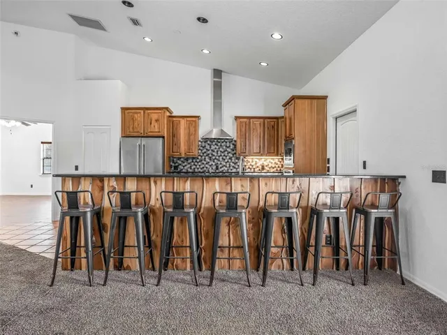 a kitchen with stainless steel appliances granite countertop a refrigerator a stove and a sink with wooden floor