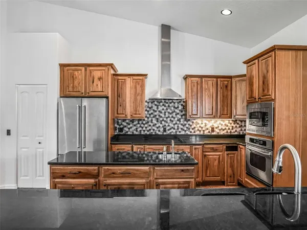 a kitchen with granite countertop a stove sink and refrigerator