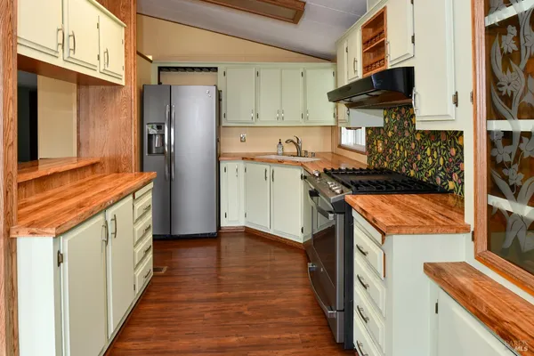 a kitchen with stainless steel appliances wooden floor and a view of living room