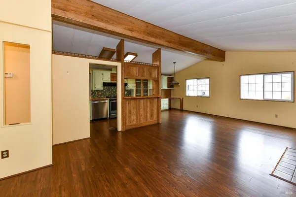 an empty room with wooden floor fireplace and windows