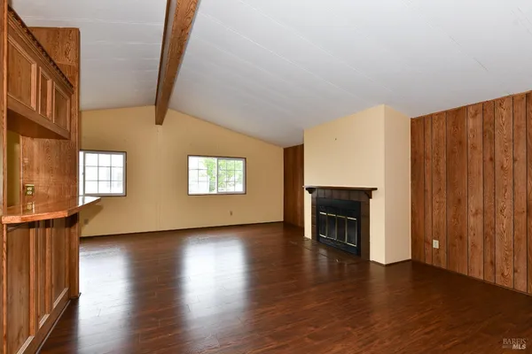 an empty room with wooden floor fireplace and windows