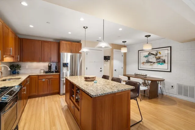 a kitchen with granite countertop a stove a sink dishwasher and a refrigerator with wooden floor
