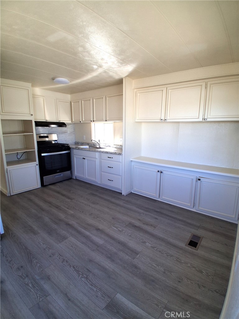 4561 Adobe Road, Unit 40 Twentynine Palms, CA 92277 - Photo 14 of 29 a large kitchen with granite countertop a stove top oven a sink dishwasher and a refrigerator with wooden floor