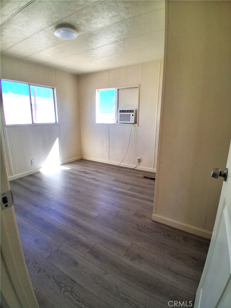 4561 Adobe Road, Unit 40 Twentynine Palms, CA 92277 - Photo 27 of 29 an empty room with wooden floor and windows