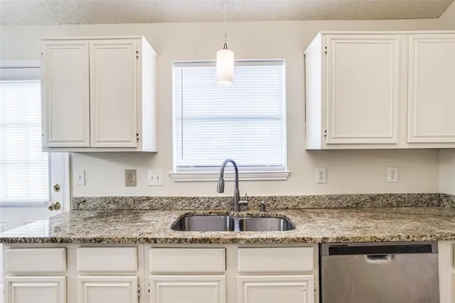 a kitchen with granite countertop white cabinets and a sink