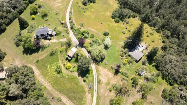 an aerial view of a houses with yard and mountain view in back