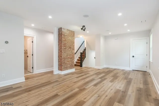 a view of an empty room with wooden floor and stairs
