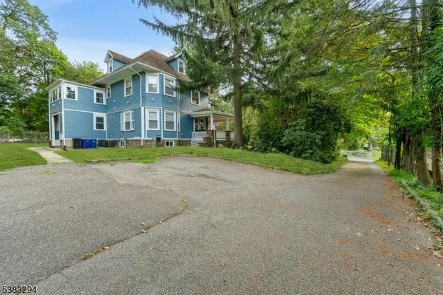 a view of a big house with a big yard and large trees