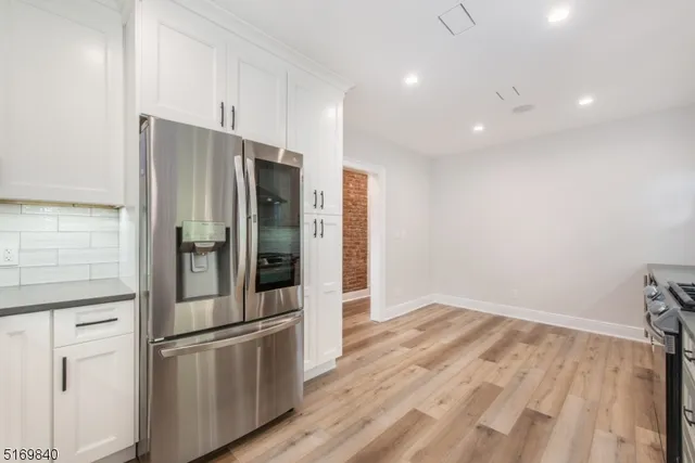 a kitchen with stainless steel appliances a refrigerator and white cabinets