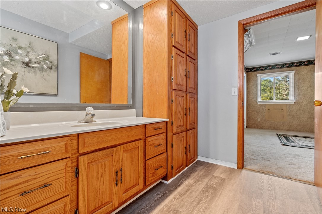 120 Lester Road New Franklin, OH 44319 - Photo 15 of 24 Bathroom with oversized vanity, mirror, light hardwood flooring, and a textured ceiling