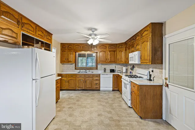 a large kitchen with a stove a refrigerator a sink a oven with a dining table and chairs