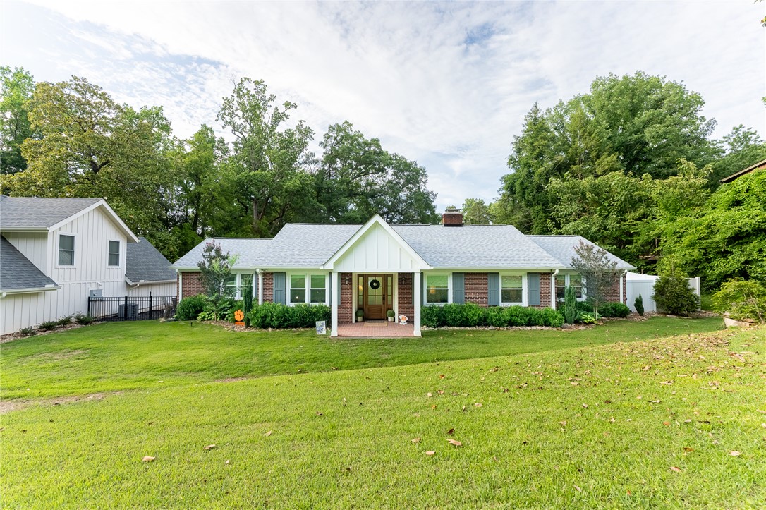 A classic brick and white siding home with a welcoming front porch and mature landscaping.