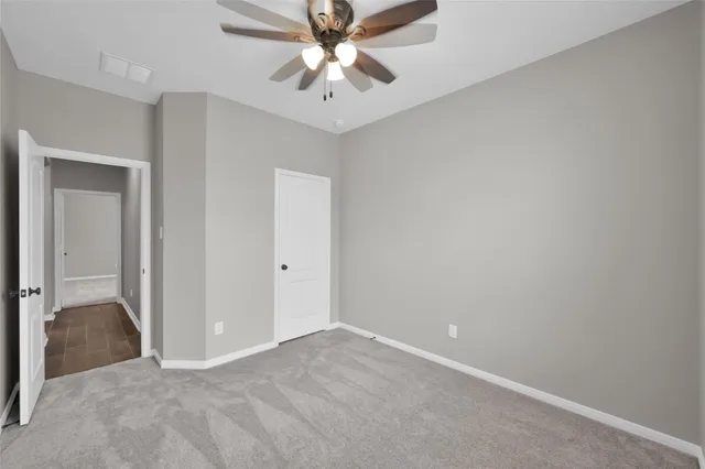 an empty room with closet and a chandelier fan