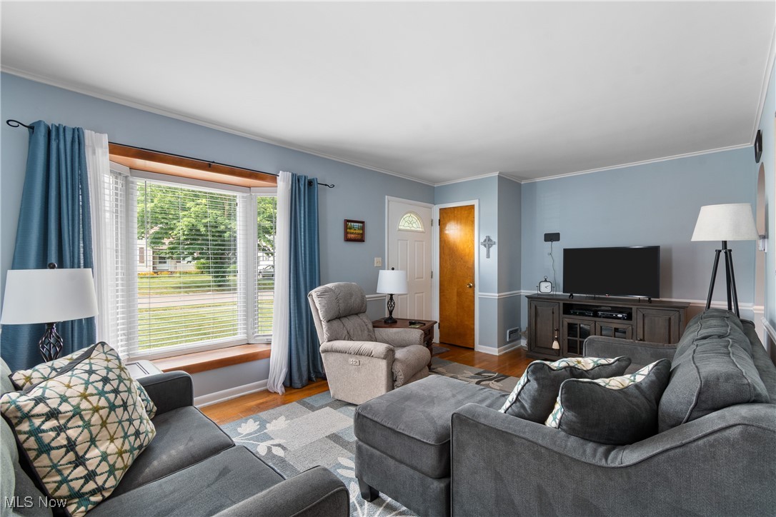 Living area featuring wood finished floors and crown molding