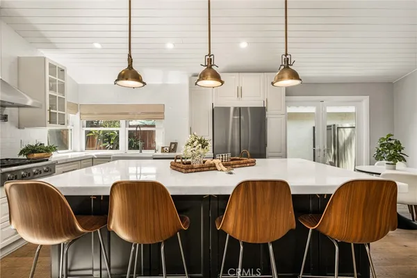 a room with stainless steel appliances kitchen island granite countertop a table chairs and a refrigerator