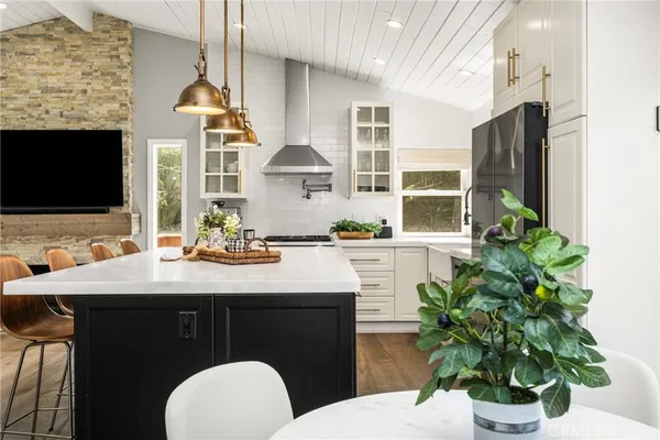 a kitchen with a sink dishwasher a stove a dining table and chairs with wooden floor